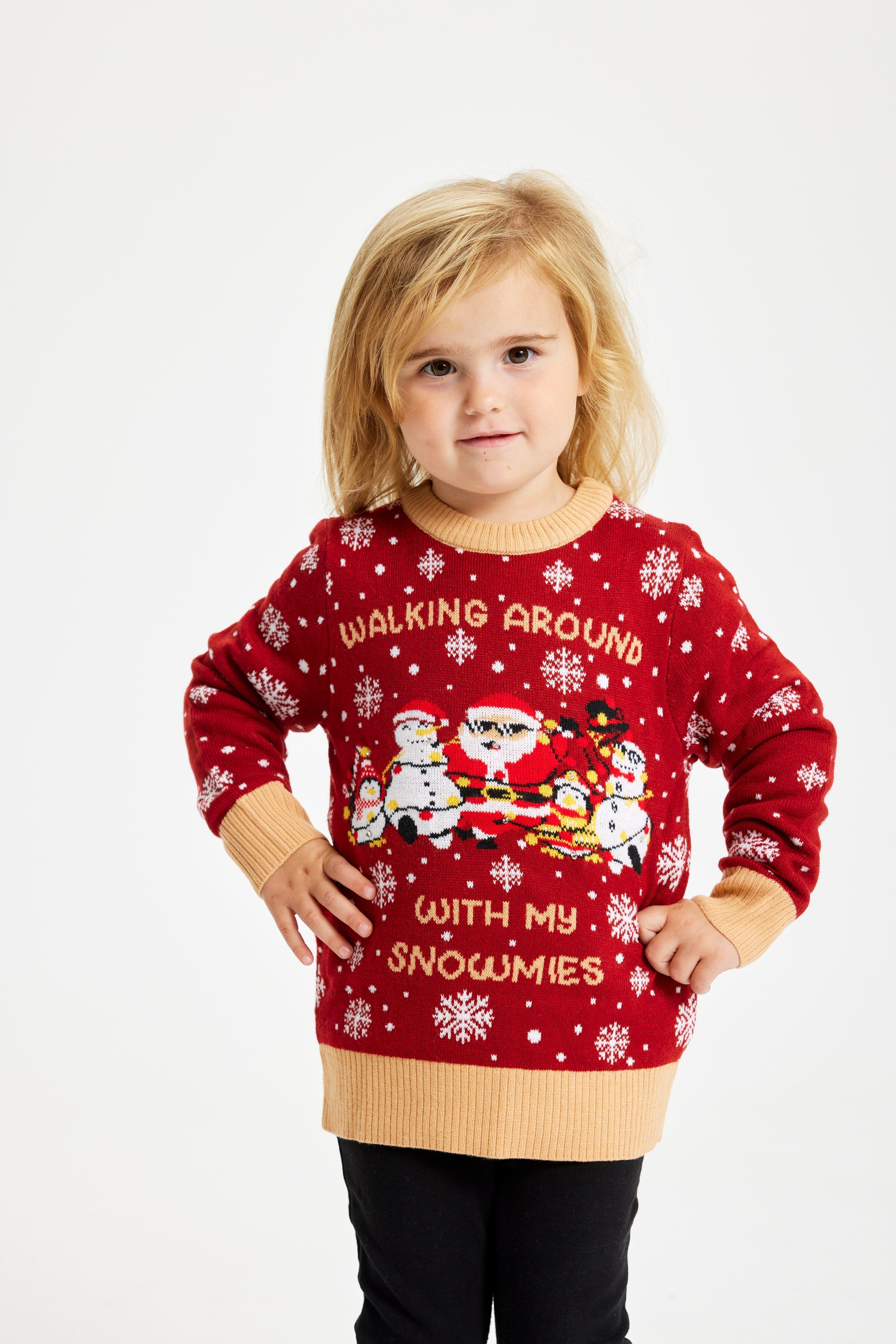 Un bambino con le mani ai fianchi che indossa un maglione natalizio rosso con la scritta